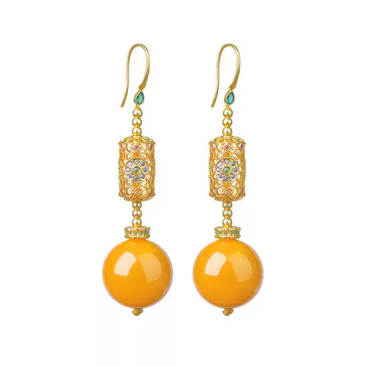 Pair of gold-tone drop earrings with orange round bead accents on a white background