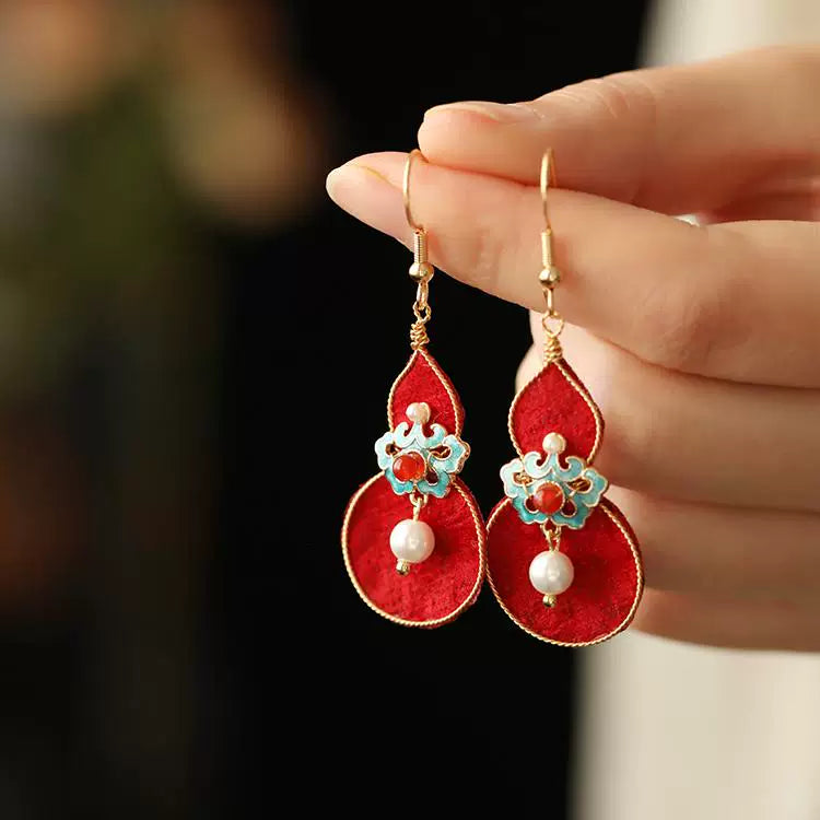 Close-up of the red gourd earrings with gold-tone hooks and white bead accents