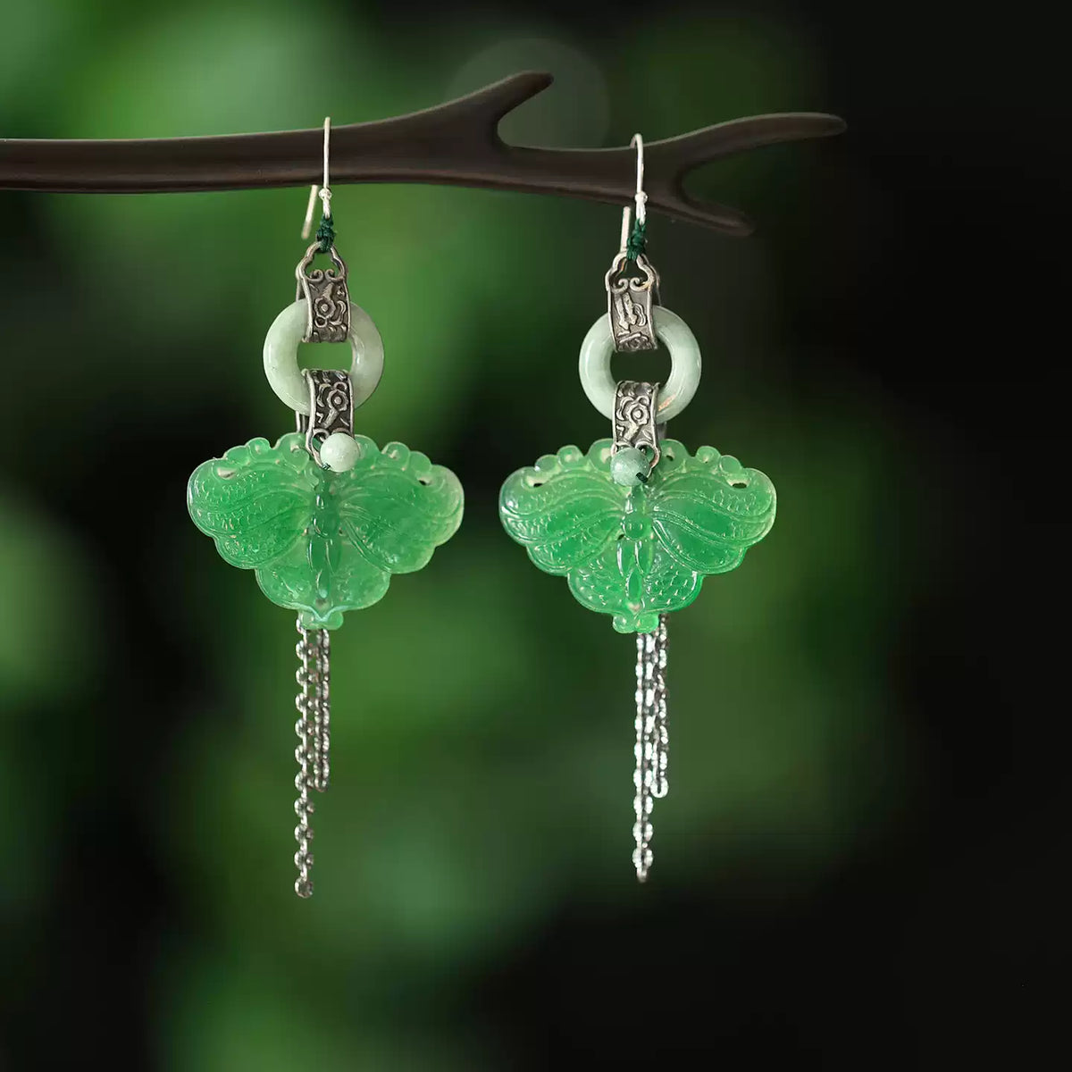 Pair of green butterfly tassel earrings on a dark green background