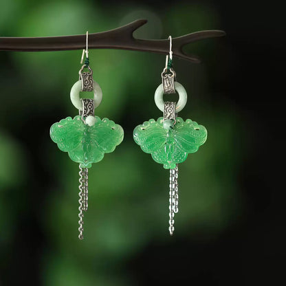 Pair of green butterfly tassel earrings on a dark green background