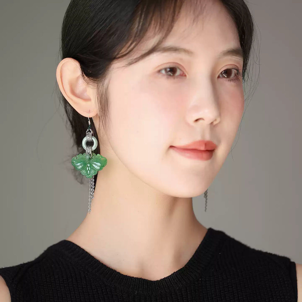 Green butterfly tassel earring worn with a black top