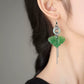 Close-up of a green butterfly drop earring on ear