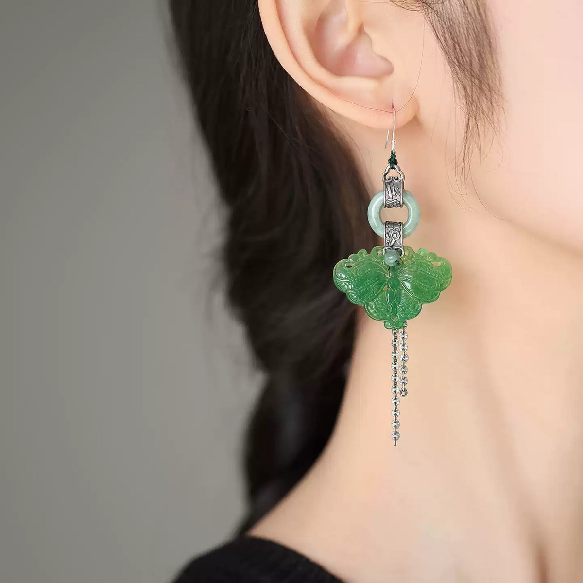 Close-up of a green butterfly drop earring on ear
