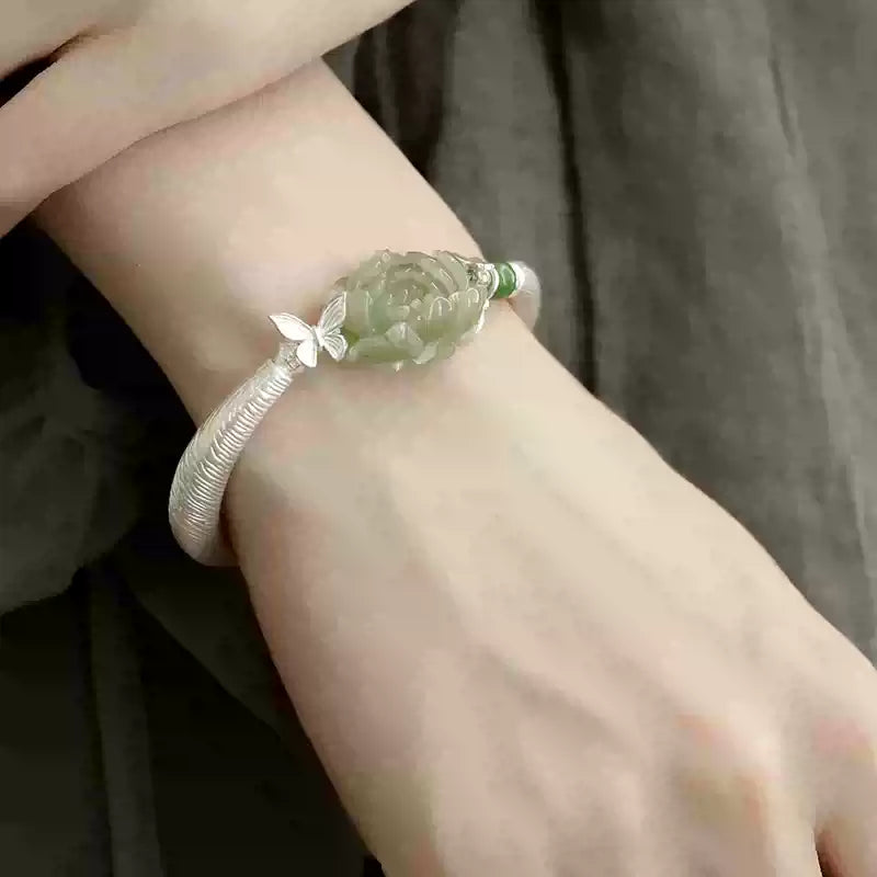 Green peony centerpiece and textured silver-tone cuff, angled wrist view