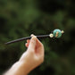 Green lotus-leaf hairpin with dark stick and gold-tone ornament
