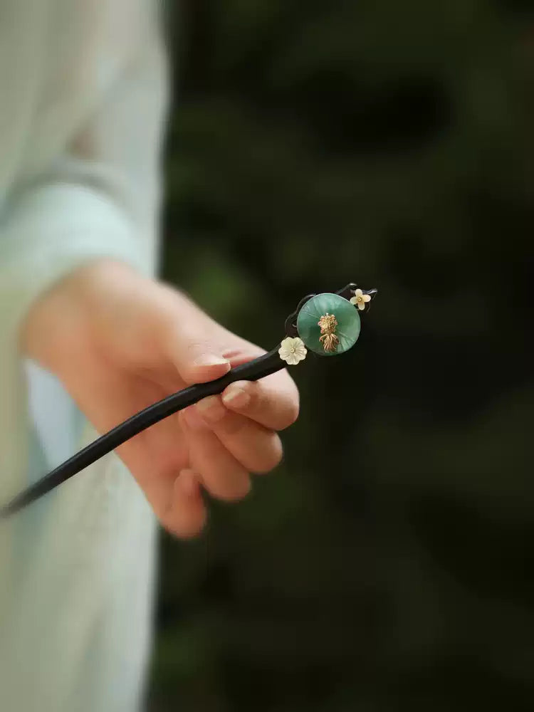 Hand-held view of the dark hair stick and lotus-leaf ornament