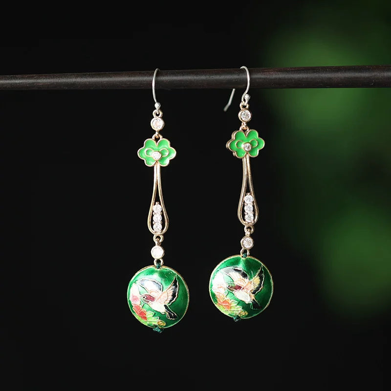 Pair of green ruyi-inspired floral drop earrings on a dark green background