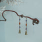 Full-length pair of Hua Ling bell drop earrings on a pale blue background