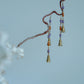 Profile view of Hua Ling bell earrings on a branch