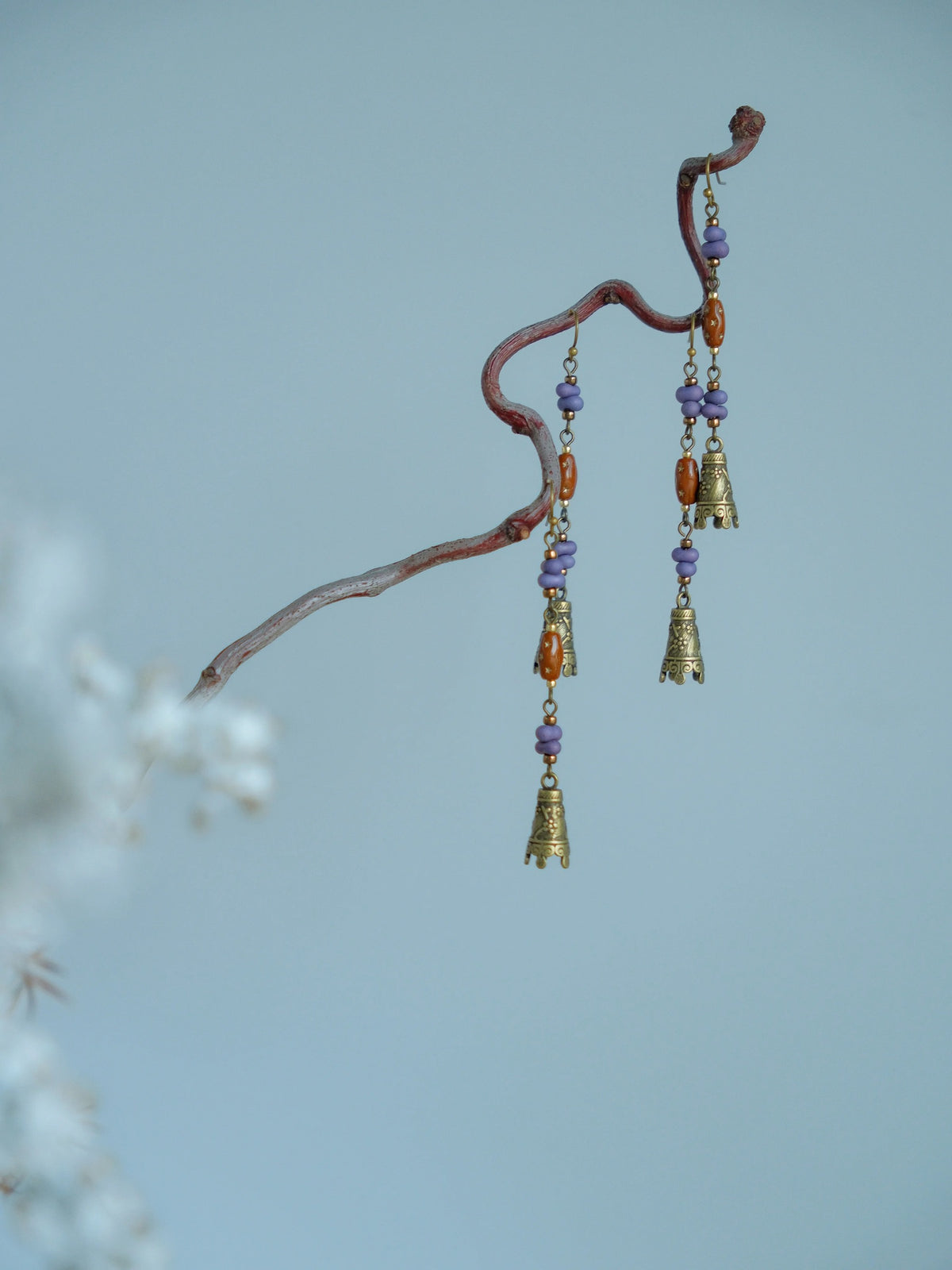 Profile view of Hua Ling bell earrings on a branch