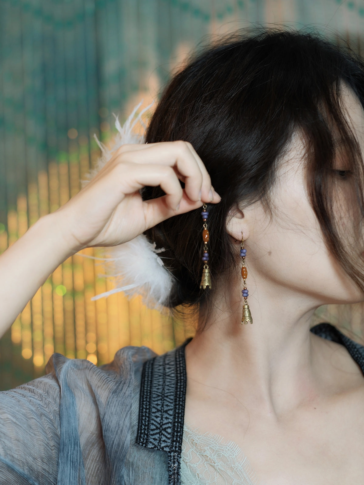 Long Chinese-inspired bell earrings shown beside the face
