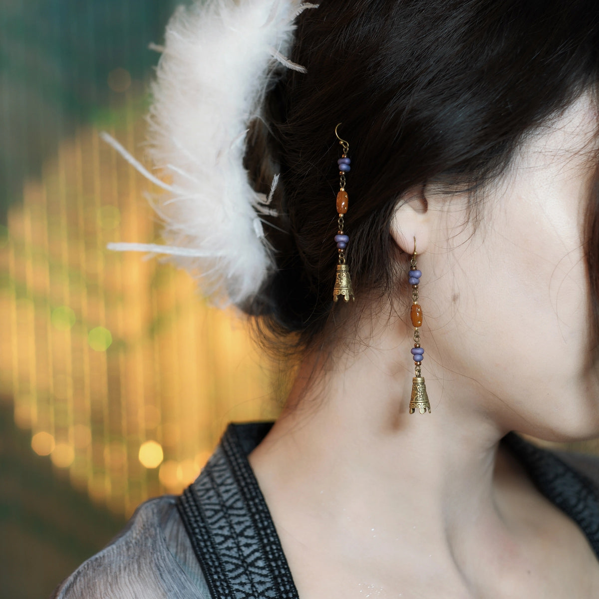 Hua Ling bell earrings with purple and amber-colored beads worn with an updo
