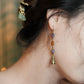 Close view of the floral bell charm and colored beads on the ear