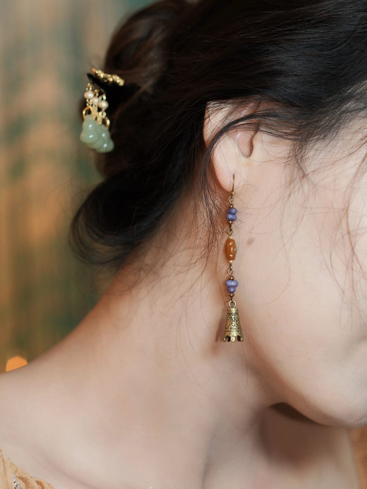 Close view of the floral bell charm and colored beads on the ear
