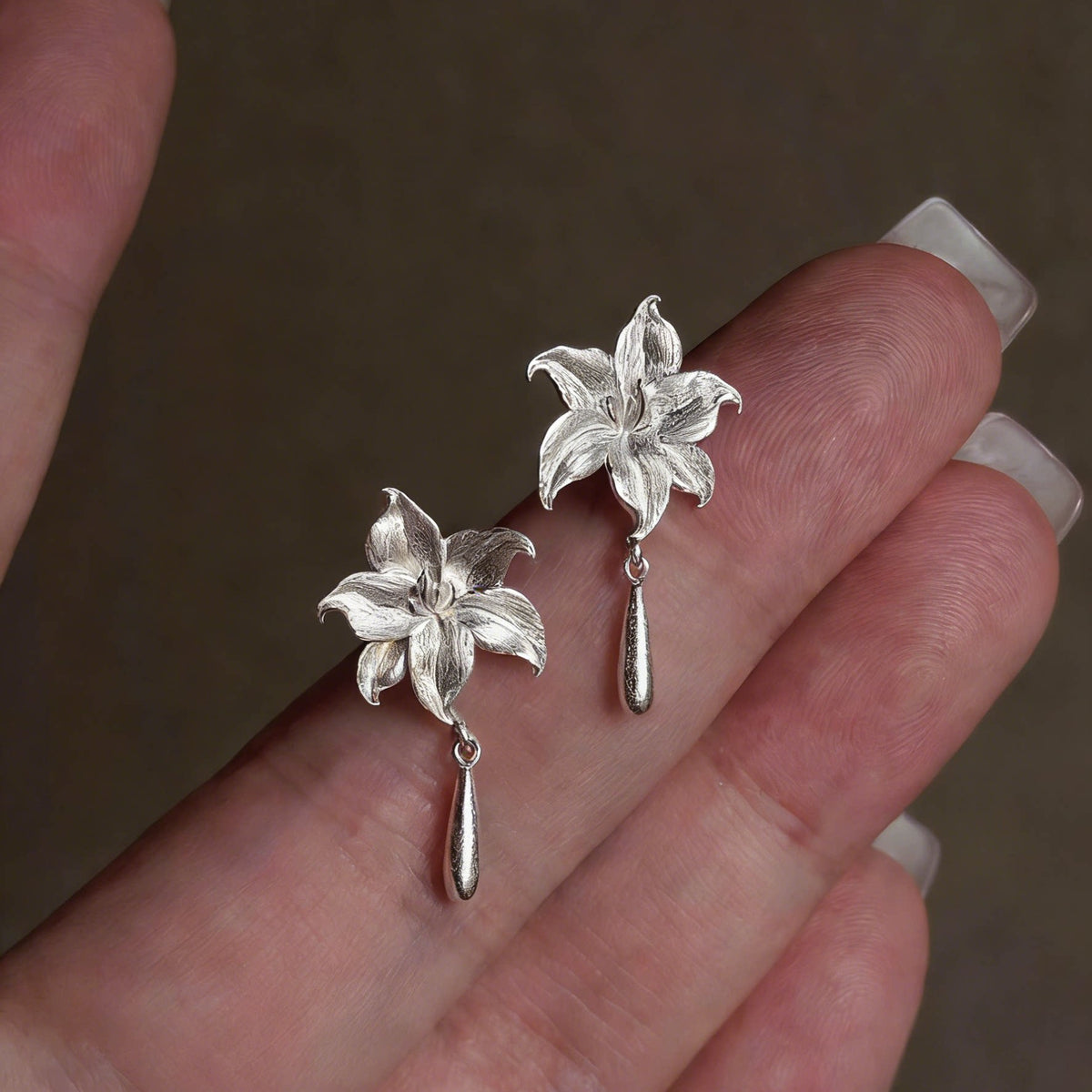 Close-up of the pair of silver-tone lily flower earrings with drop details