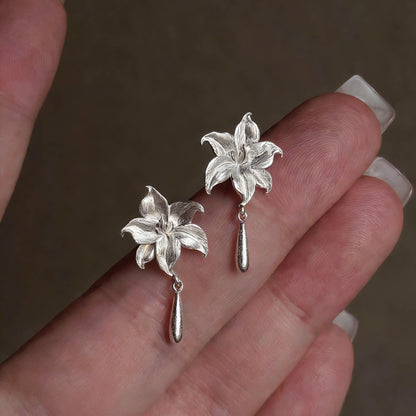 Close-up of the pair of silver-tone lily flower earrings with drop details