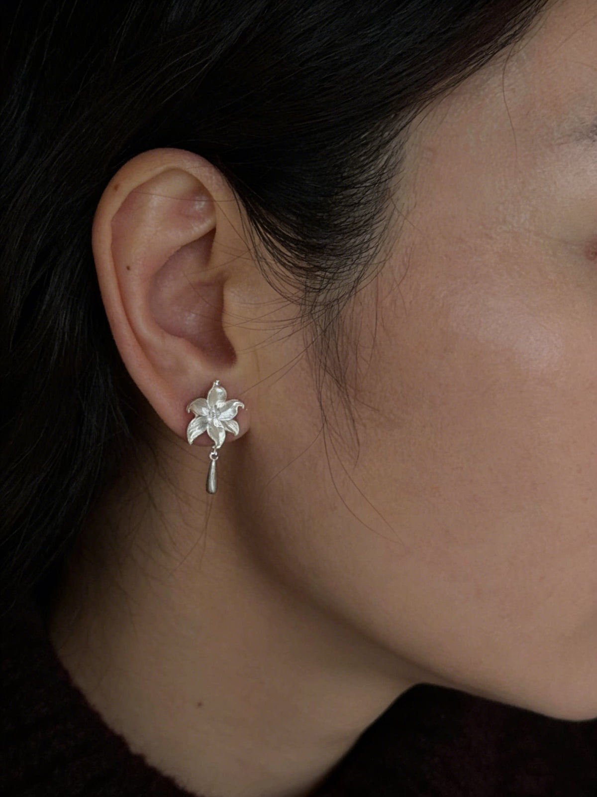 Side view of the lily flower earring worn on the ear