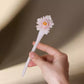 Hand-held view of the pale pink peony ceramic hairpin