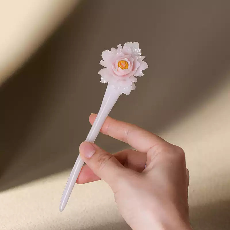 Hand-held view of the pale pink peony ceramic hairpin