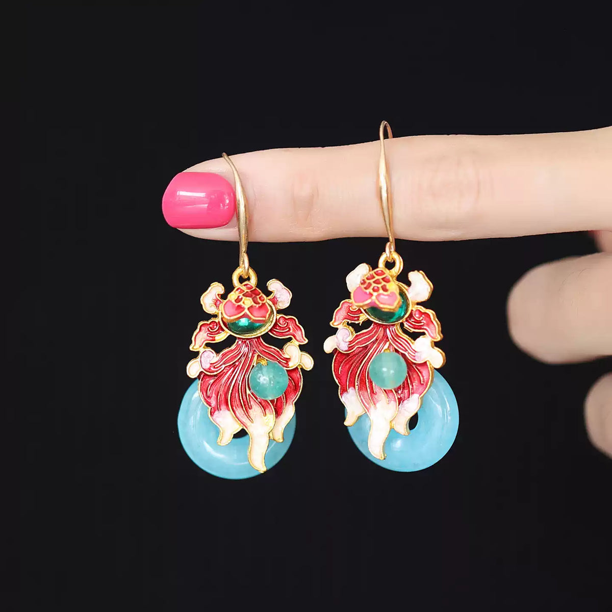 Hand-held detail of the colorful koi fish drop earrings