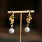 Koi fish drop earrings with green imitation jade accents and white round drops on a display stand