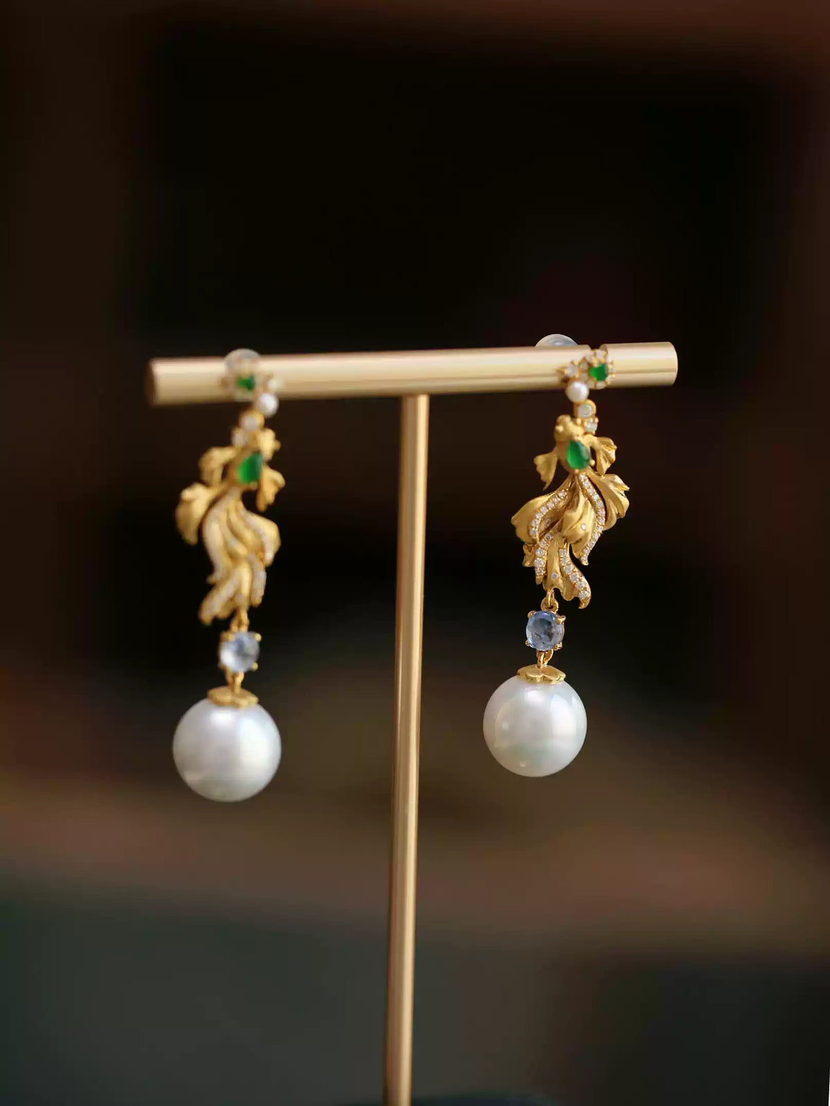 Koi fish drop earrings with green imitation jade accents and white round drops on a display stand