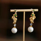 Close view of gold-tone koi earrings showing green imitation jade accents and filigree detail