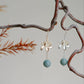 Pair of lotus flower drop earrings hanging from a branch, hook style