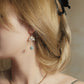 Close-up of Lian Yi lotus and blue-green bead earring worn with a silver hook
