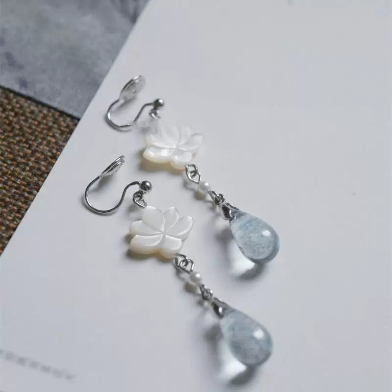 Clip-on mother-of-pearl lotus earrings with blue-gray teardrop pendants