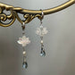 Lotus drop earrings hanging from a decorative brass display
