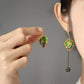 Green koi enamel-style drop earring shown beside a hand