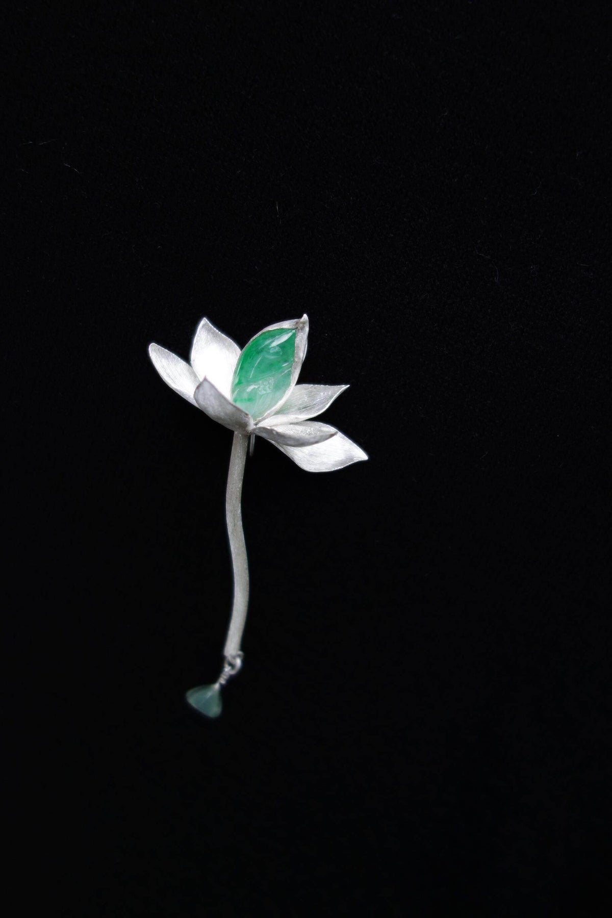 Sculpted lotus waterdrop brooch with green accent on dark background