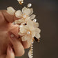 Magnolia floral side clip with pearl-like drops, held in hand