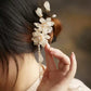 Magnolia tassel hair clip shown in a hand for scale