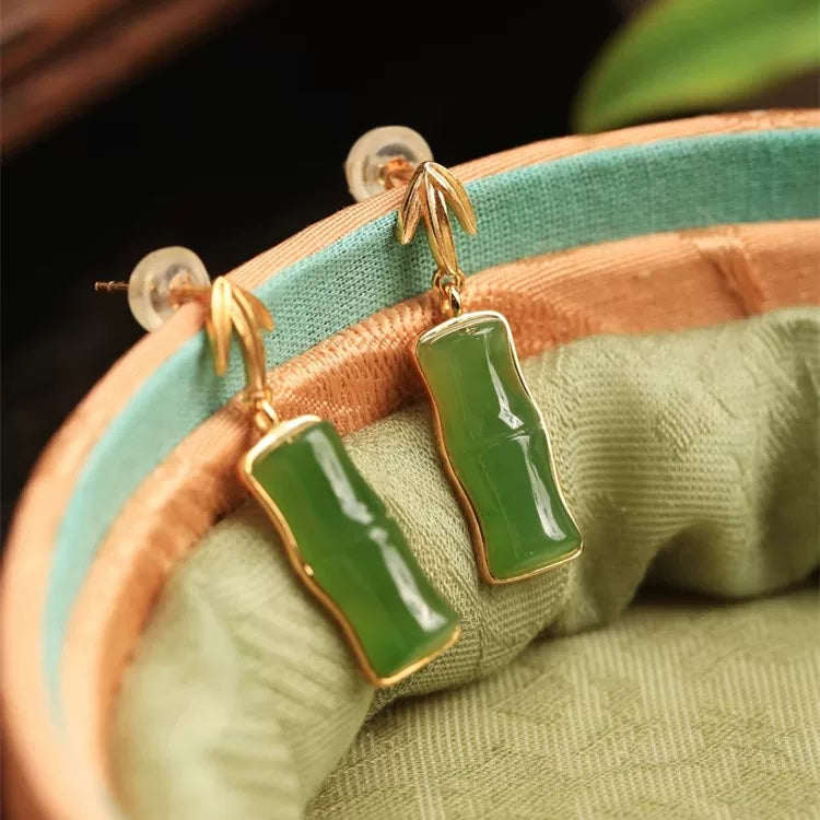 Pair of green bamboo segment stud earrings with gold-plated details, displayed on fabric