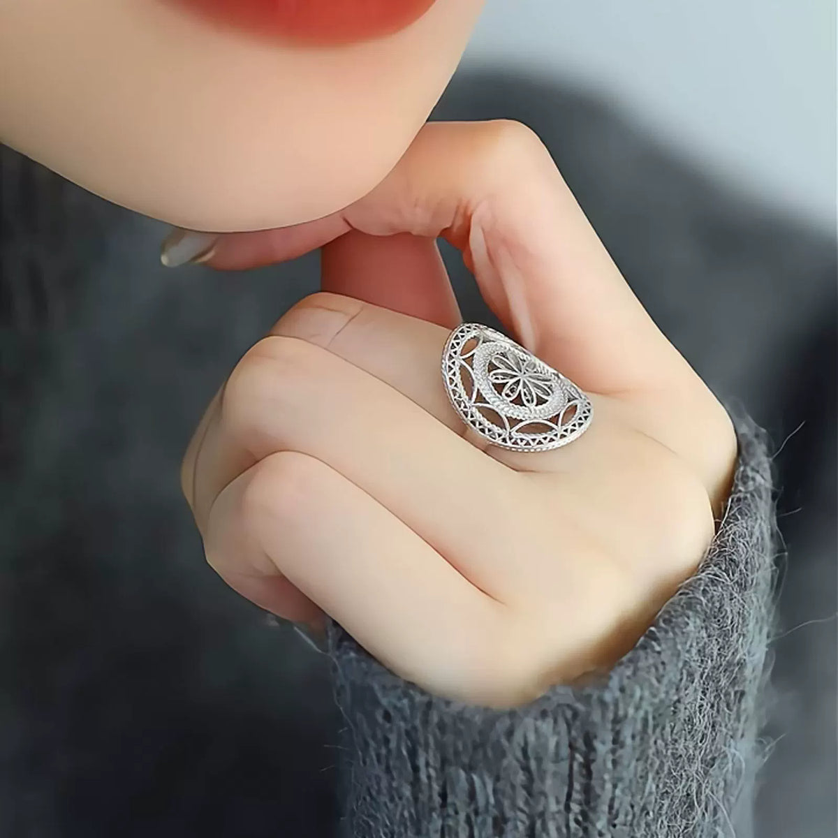 Angled view of the ring's openwork floral face on a hand