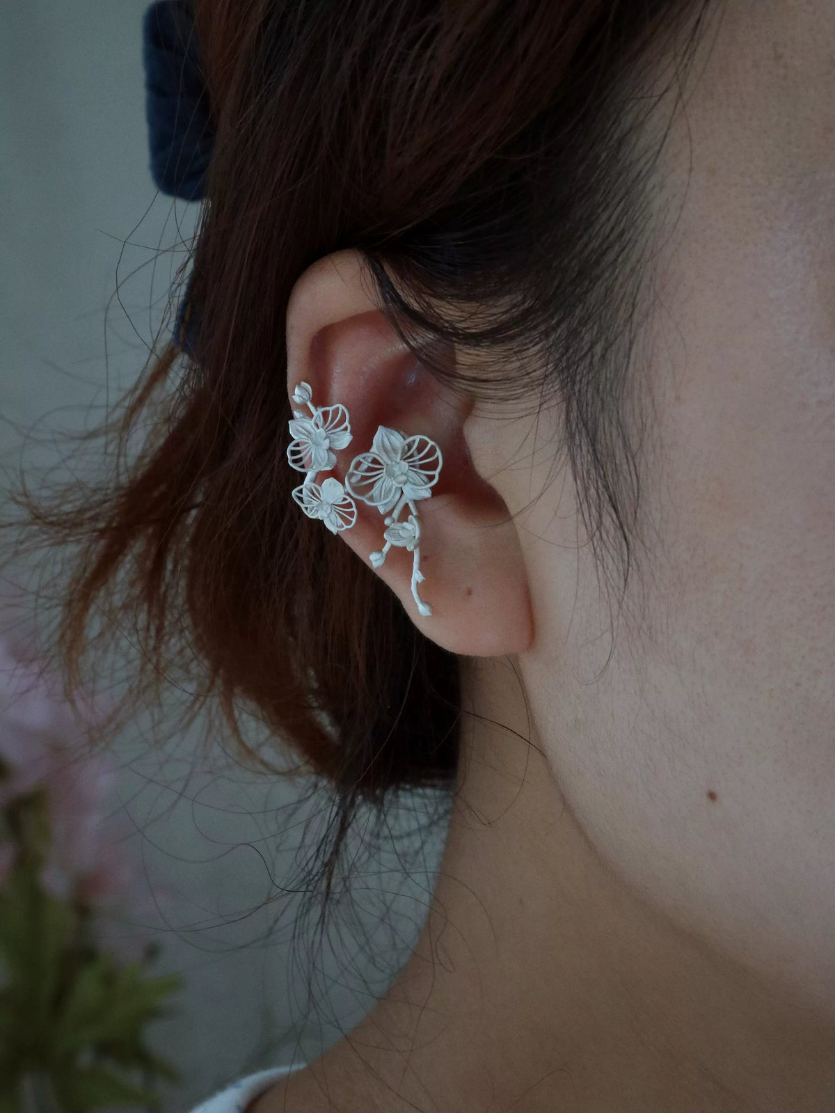 Side view of the orchid ear cuff worn on the ear