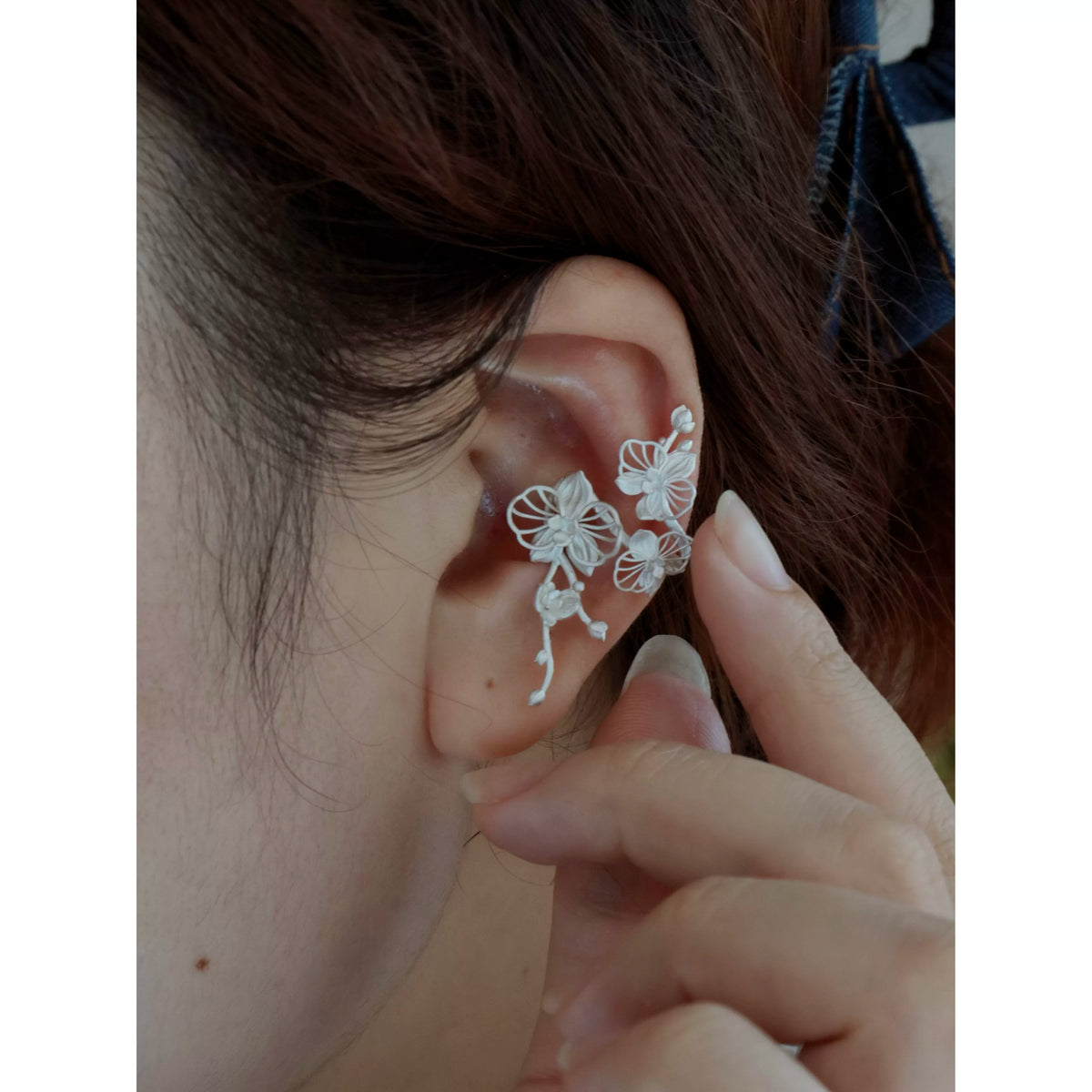Close-up of the orchid ear cuff worn on the ear