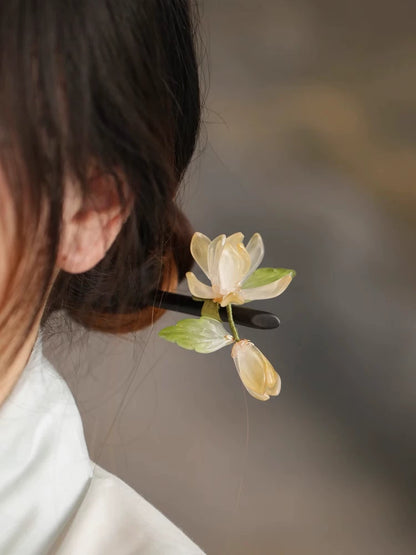 Light yellow orchid hair stick shown worn in a bun