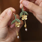 Golden osmanthus and leaf tassel earrings shown in hand