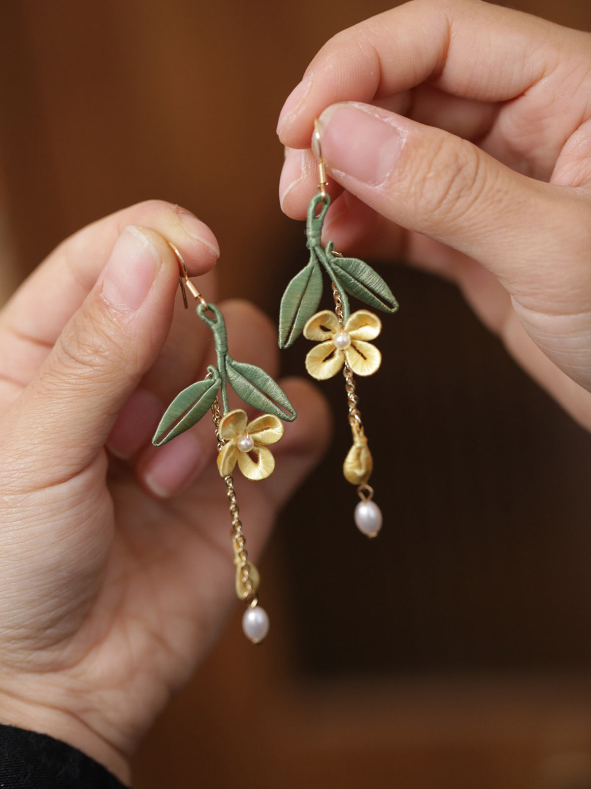 Golden osmanthus and leaf tassel earrings shown in hand