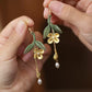 Hand holding the golden osmanthus leaf tassel earrings