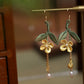 Pair of yellow osmanthus and green leaf drop earrings, close-up