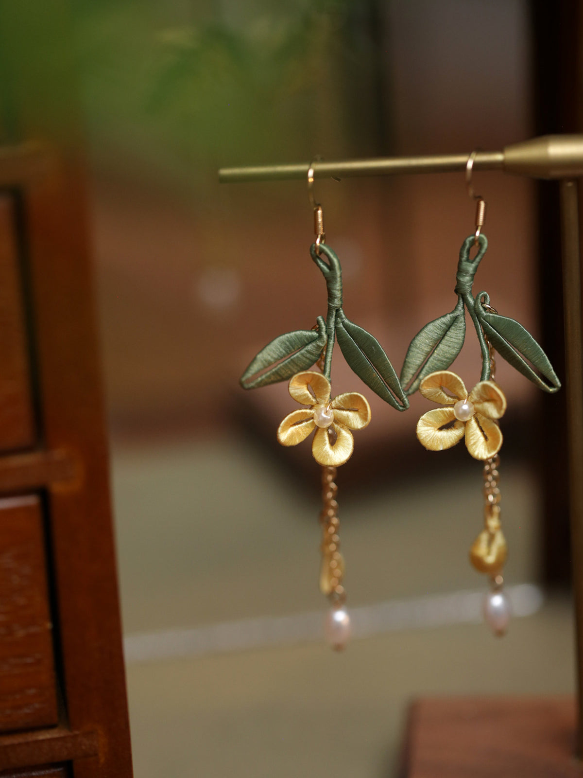 Pair of yellow osmanthus and green leaf drop earrings, close-up