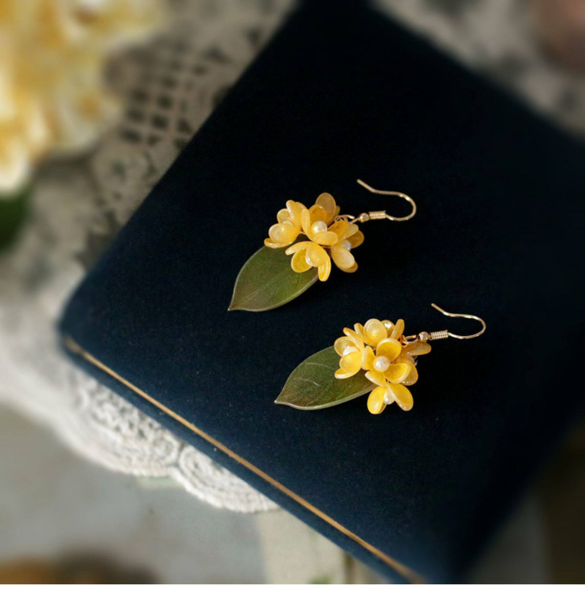 Short gold-tone osmanthus flower and green leaf earrings shown as a pair