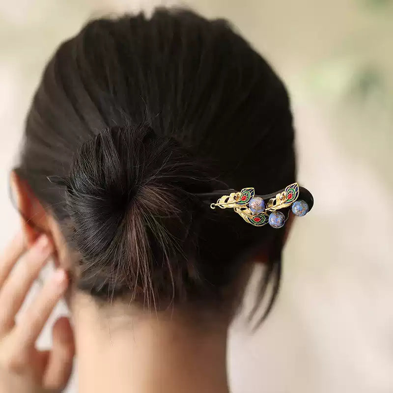 Peacock-inspired dark wood hairpin worn in a bun