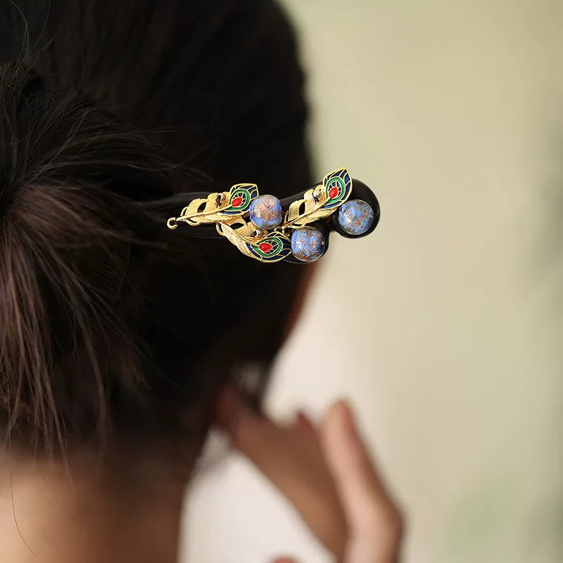 Close-up of a peacock-inspired hairpin with colorful enamel details