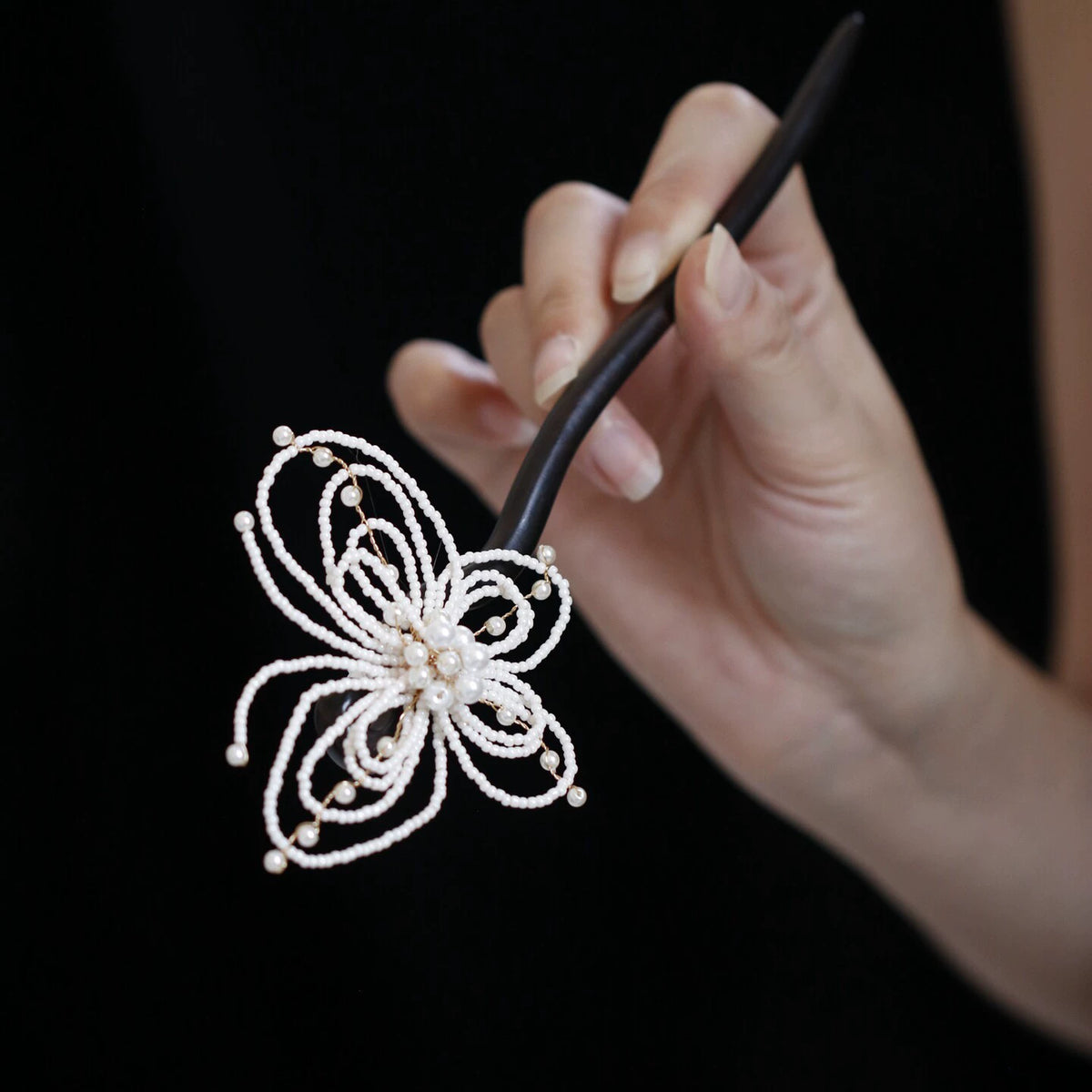 Pearl-beaded openwork butterfly wooden hairpin held in hand