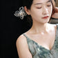 Model wearing a pearl-beaded butterfly hairpin in an updo